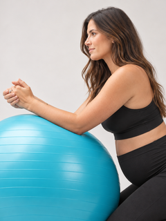 Person leaning forward over a blue BelleVie BumpFlow exercise ball